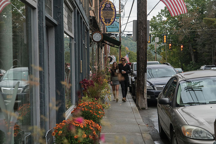 Man and woman walking on a sidewalk in a small town.