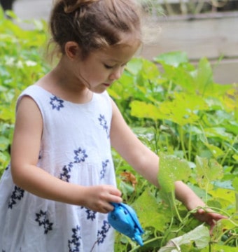 Girl in white dress besides green plant