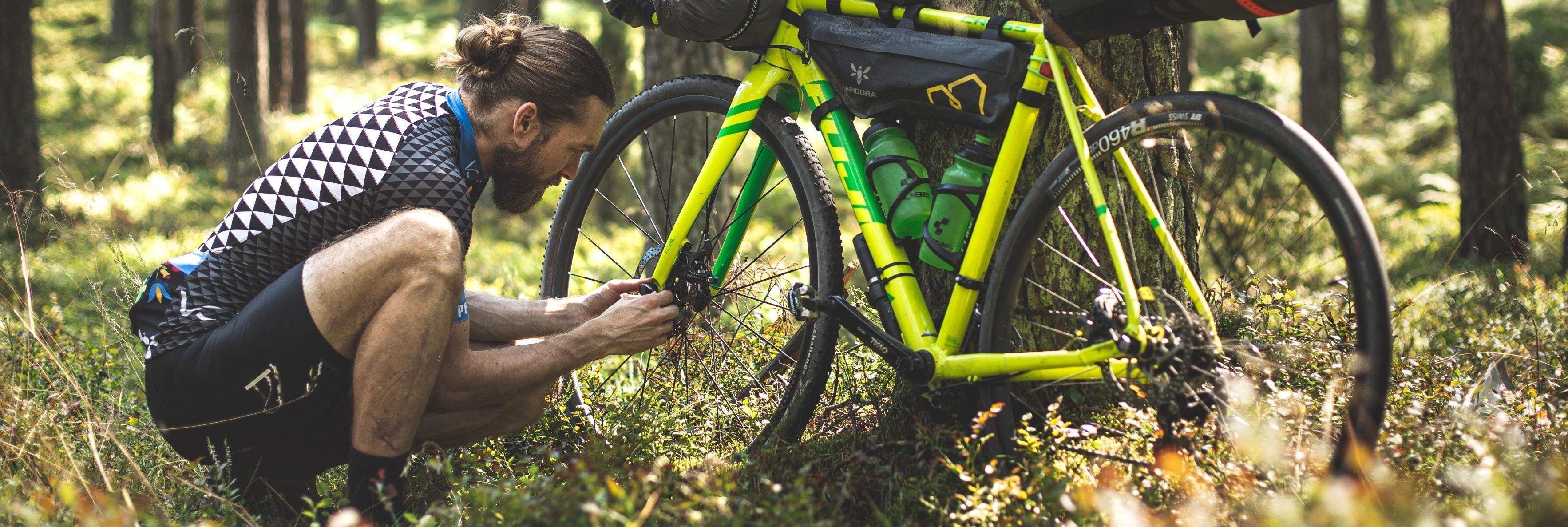 man fixing bike in forest