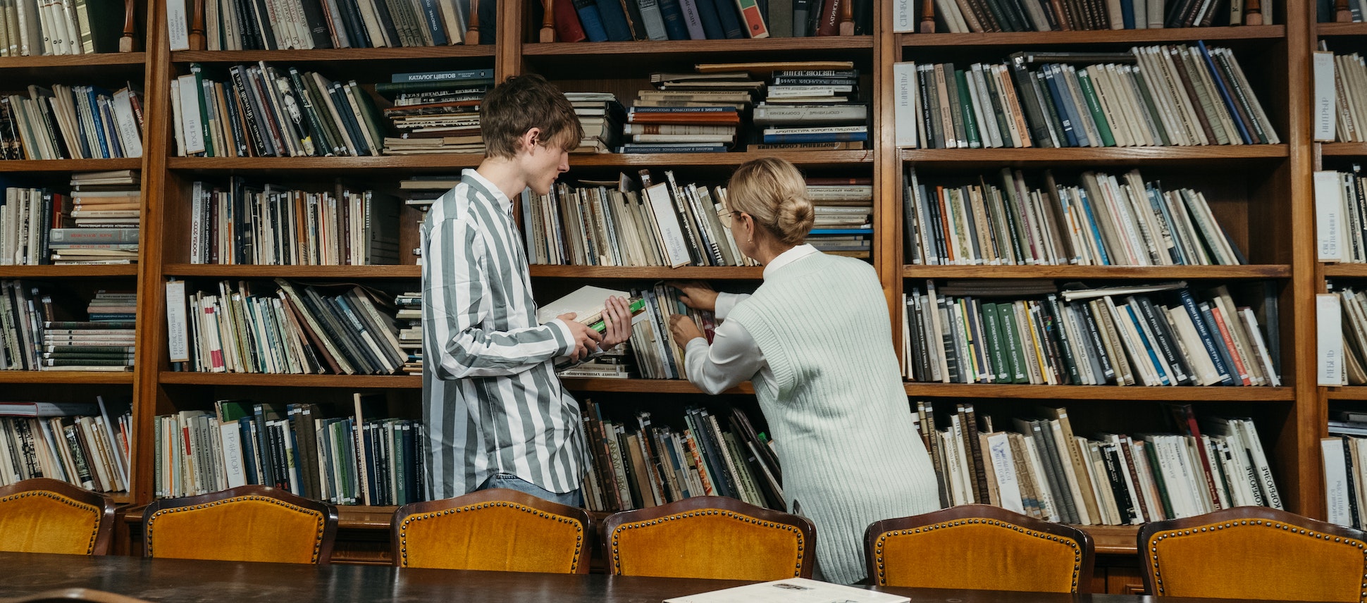 Picture of a librarian showing a young man how to shelve books at a public library.