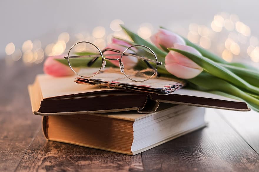 a picture of some flowers and reading glasses on top of couple of boxes