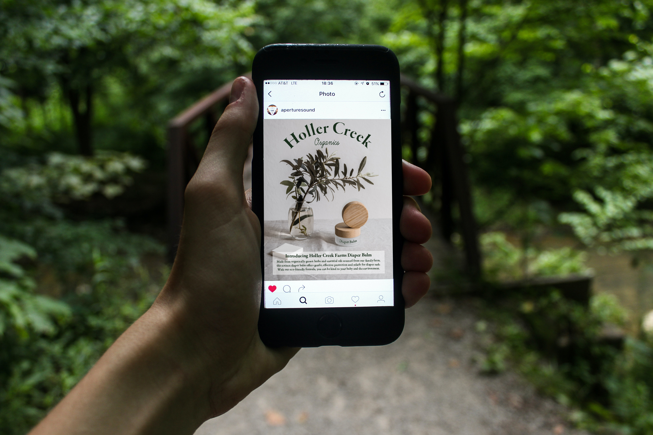 Phone displaying Holler Creek Farm Social Media reel with picture of diaper balm on a tan tablecloth next to a plant