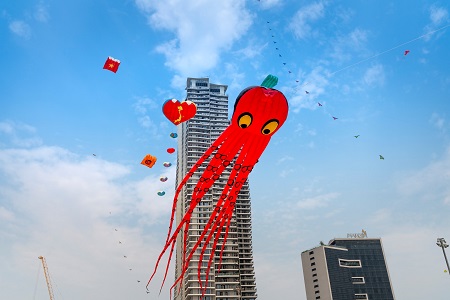 big red octopus kite in the sky with two tall buildings in the back