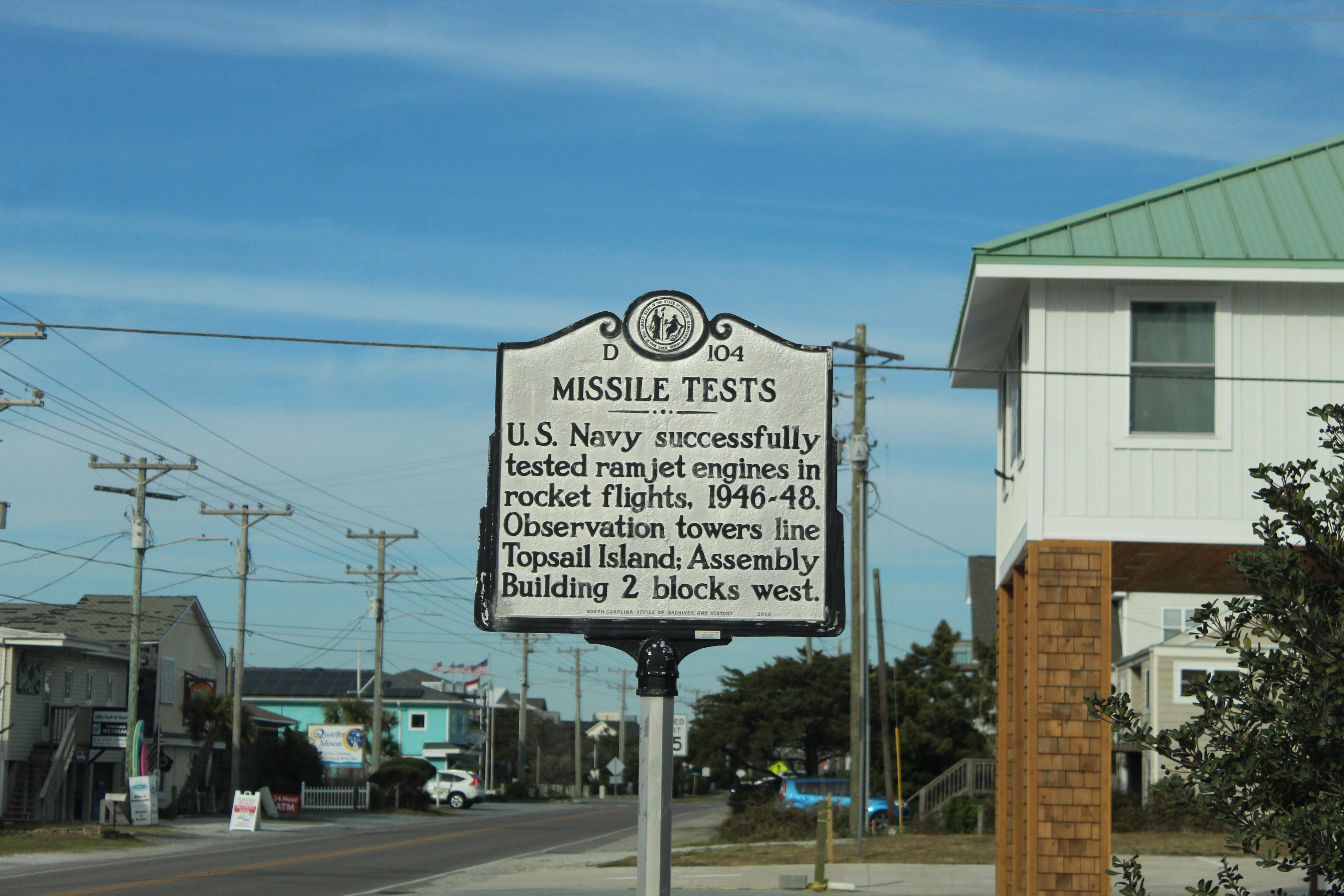 A sign commemorating the history of the area which reads 'U.S. Navy successfully tested ramjet engines in rocket flights. 1946-48. Observation towers line Topsail Island. Assembly Building 2 blocks west.'