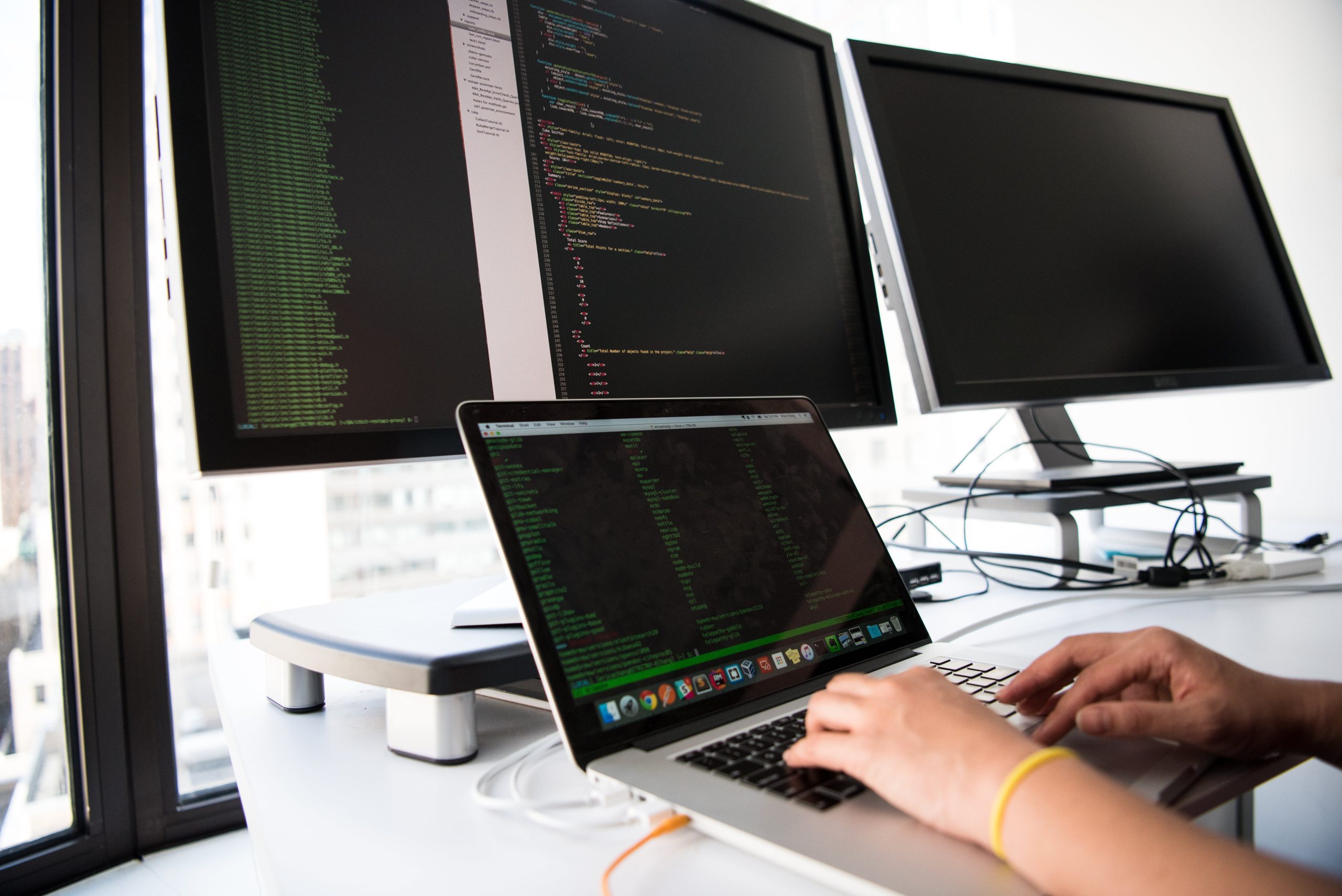 Person conducting web development with use of three monitors.