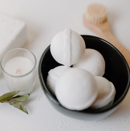 five bath bombs in a black bowl with a candle on a side
