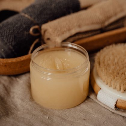 sugar scrub in a small container with a small towel next to it