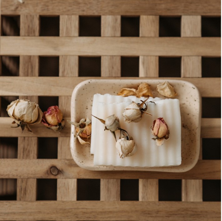 Soap bar in a soap dish with rose petals on top and sides