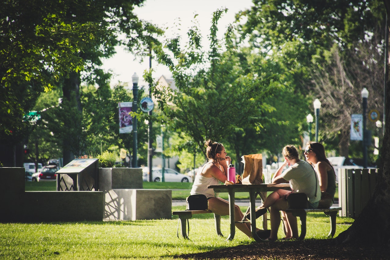 friends sitting together at a bench in a park