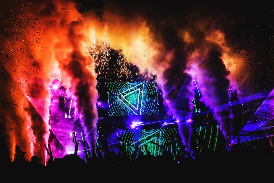 EDM concert with laser lights, neon color lights, and smoke