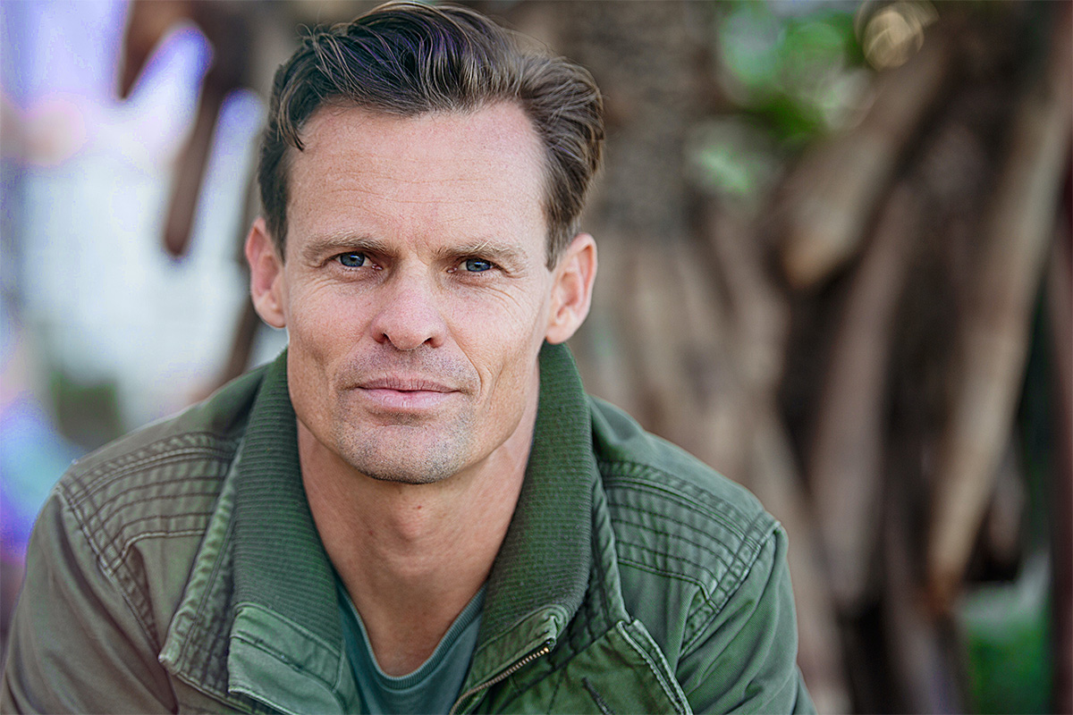 man with blue eyes and green jacket