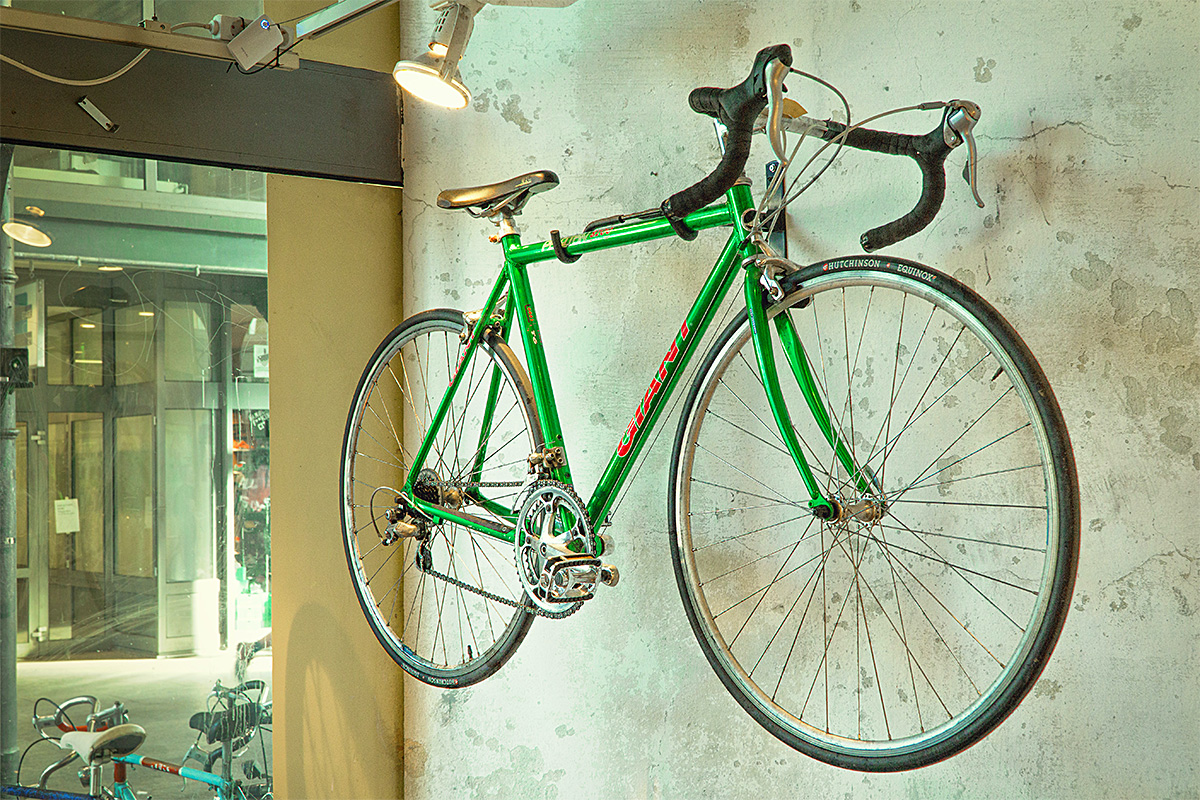 green road bicycle hanged on a wall